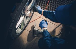 A car mechanic is working a car tire in a garage.