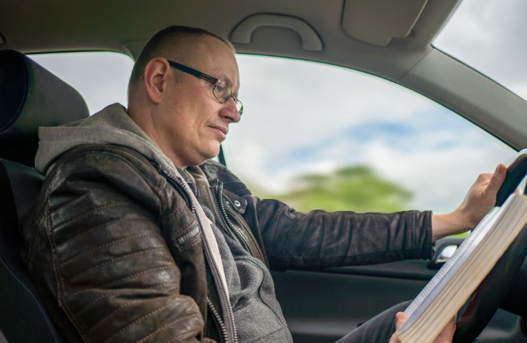 A man reading a book in his car