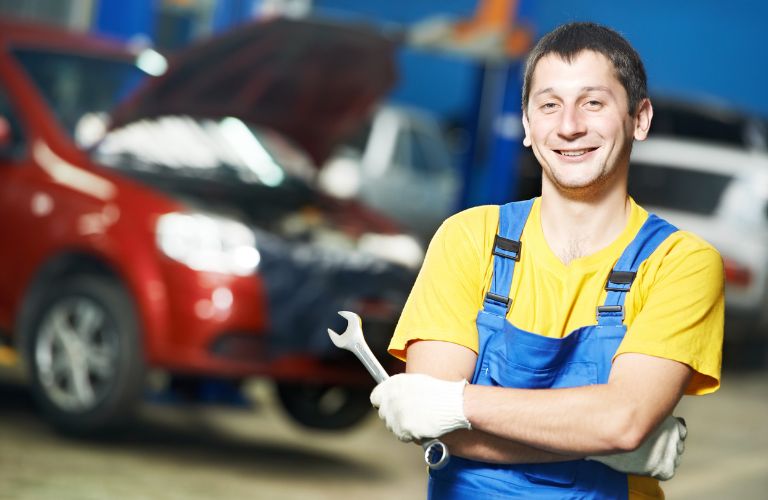 a technician who is working under the hood of a car posing