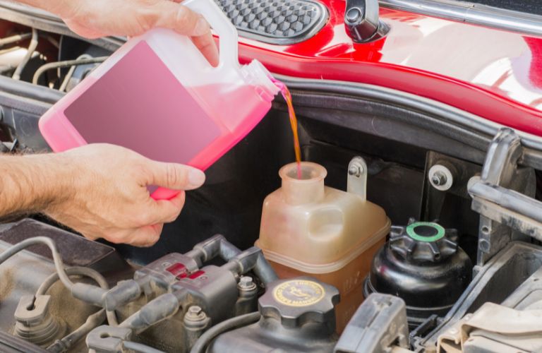 Close up of a hand pouring oil in a car.