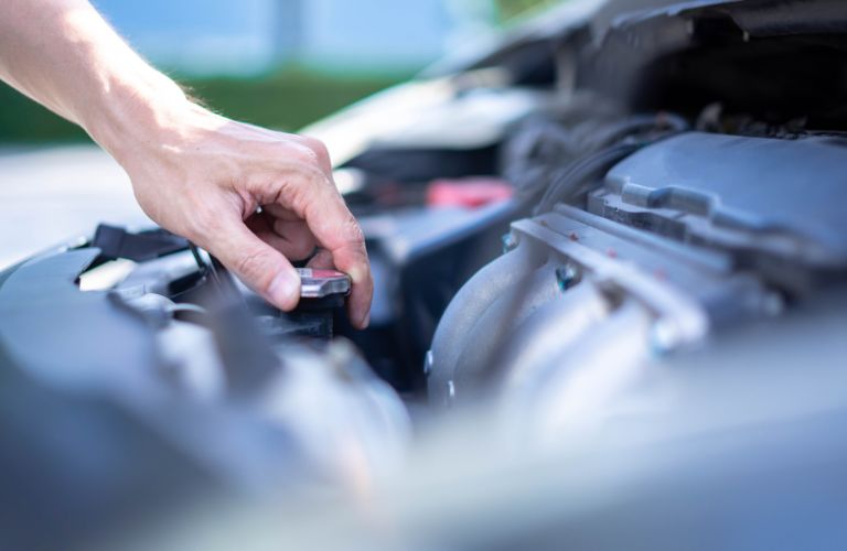 Close up of a hand's checking the coolant level of a car.