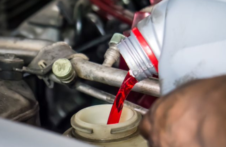 A man adding transmission fluid to a vehicle 